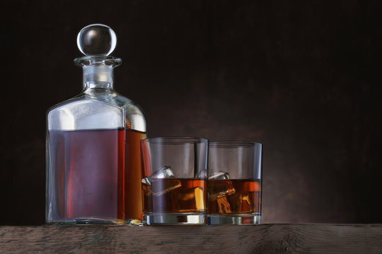 Bottle of whiskey with glasses on brown background