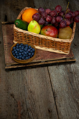 Different fruits in a basket. A large set of vitamin fruits. Healthy diet food. Vegan Food. Apples, bananas, pears, kiwi, grapes, pomegranate, avocado.