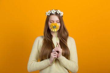 beautiful young woman with a wreath on her head on a yellow background