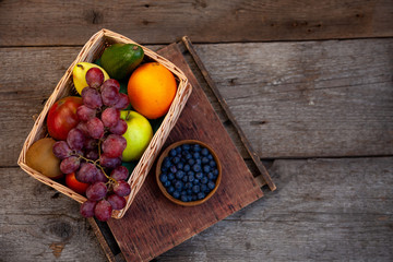 Fruit basket on a wooden kitchen table. Assorted fruits, set. Different multi-colored fruits. Vitamin nutrition.