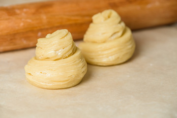 Modern trend baking in 2020-cruffins, puffmuffin, a mixture of croissants and muffins. On a dark wooden table sprinkled with powdered sugar. the process of making buns.