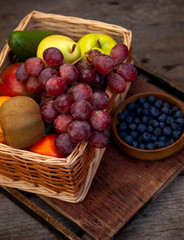 Different fruits in a basket. A large set of vitamin fruits. Healthy diet food. Vegan Food. Apples, bananas, pears, kiwi, grapes, pomegranate, avocado.