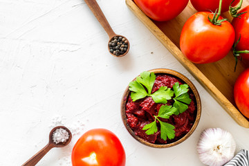 Homemade tomato sause near ingredients - garlic, spices - on white background top-down copy space