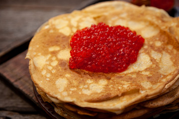 A stack of thin pancakes in a slide of red caviar.