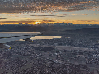 airliner flight over Geneva airport at sunrise over the Swiss and French Alps