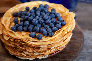 Homemade thin pancakes with blueberries. Pancake on a plate with berry filling. Shrovetide. Breakfast on a wooden table. Baking from batter. Fresh pancakes on a plate. 