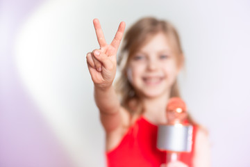 Baby 7 - 8 years old, cute charming blonde girl with blond hair sings in the device, bluetooth...