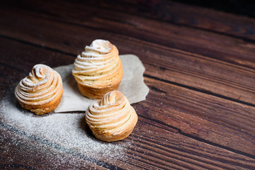 Modern trend baking 2020-cruffins puff muffin , a mixture of croissants and muffins. On a dark wooden table sprinkled with powdered sugar. Place to copy, view from above