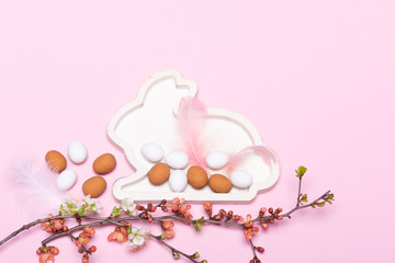Osterdeko mit Eiern, Blütenzweigen und Osterhasen vor rosa Hintergrund