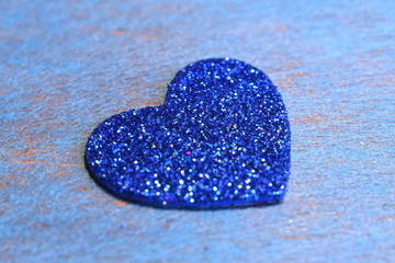 Blue shiny heart on a blue background close up.