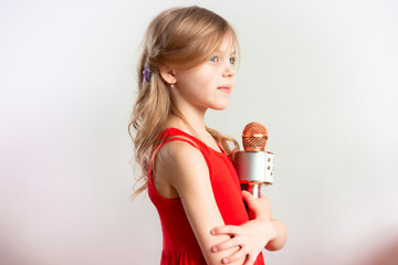 child 7 - 8 years old, cute charming fair-haired girl with blond hair singing in a device,...