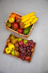 Fruit basket with place for text. Set of different fruits on a wooden kitchen table. Vitamin nutrition, healthy food. Red grapes, blueberries, mangoes, orange, apple, kiwi.