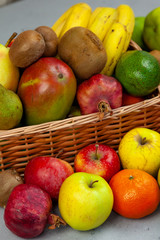 Fruit basket with place for text. Set of different fruits on a wooden kitchen table. Vitamin nutrition, healthy food. Red grapes, blueberries, mangoes, orange, apple, kiwi.