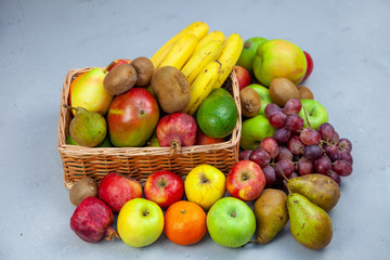 Fruit basket with place for text. Set of different fruits on a wooden kitchen table. Vitamin nutrition, healthy food. Red grapes, blueberries, mangoes, orange, apple, kiwi.