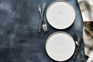 White craft plate, cutlery and napkin on dark stone table. Top view, copy space, Table setting....