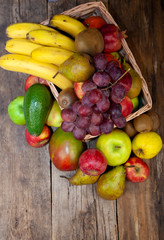 Fruit background with place for text. Different fruits assorted on a wooden table. Vitamin food. Apples, pears, bananas, oranges, kiwi, mango, avocado. A set of healthy food. Frame of fruits. 