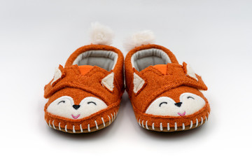 Cute orange fox shaped baby slippers isolated on white background.