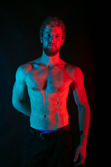 Fototapeta premium Male wrestler posing . studio black-white background, red and blue lights.