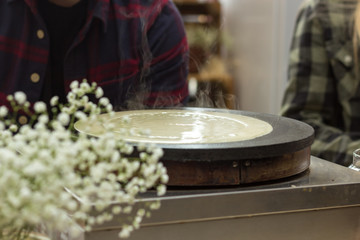 Close-up soup ladle with dough and oven. The dough is pouring on a crepe maker. A series of photos. Step-by-step photo recipe for pancakes.