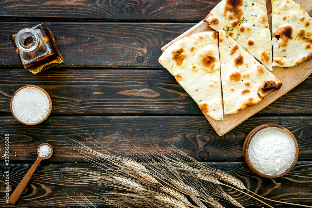 Wall mural focaccia ingredients. wheat ears, flour, oil near bread on dark wooden background top-down copy spac