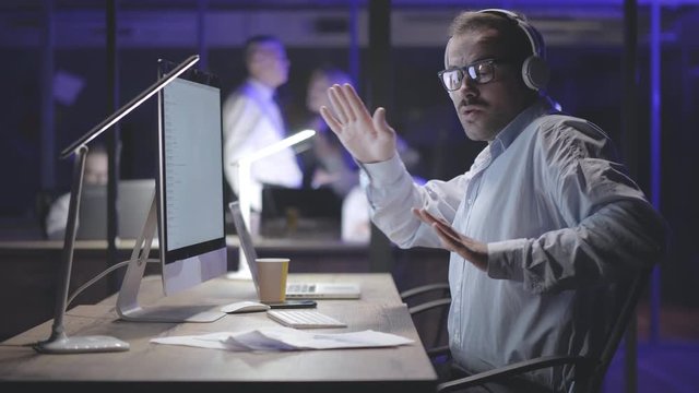 Male worker listening to music, relaxing during work break in night office