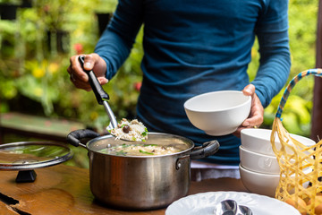 A man scooping rice soup into a bowl. Asian food in the morning.