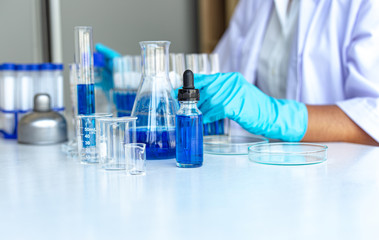 Fototapeta premium Scientists are carrying blue chemical test tubes to prepare for the determination of chemical composition and biological mass in a scientific laboratory, Scientists and research in the lab Concept.