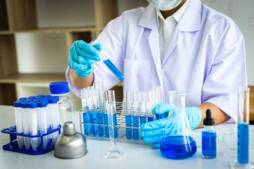 Fototapeta premium Scientists are carrying blue chemical test tubes to prepare for the determination of chemical composition and biological mass in a scientific laboratory, Scientists and research in the lab Concept.