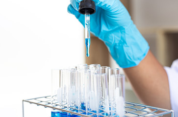 Scientists are carrying blue chemical test tubes to prepare for the determination of chemical...