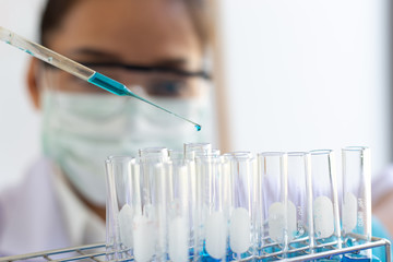 Scientists are carrying blue chemical test tubes to prepare for the determination of chemical composition and biological mass in a scientific laboratory, Scientists and research in the lab Concept.