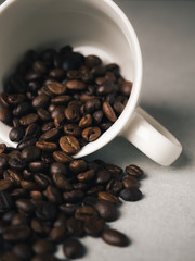 Close-up of roasted Thai coffee beans spilling in fall white coffee cup. Photo filtered in vintage style.