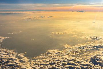Beautiful sunrise sky above clouds with dramatic light. Cabin view from airplane