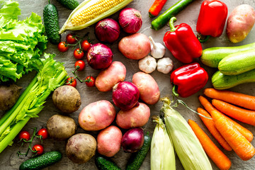 Fresh vegetables still life. Potato, cucumber, beet carrot, greenery on stone background top-down