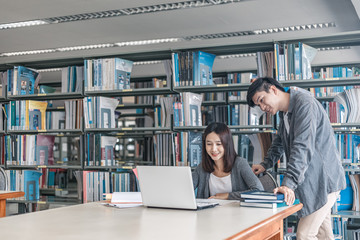 High school or college students studying and reading together in library. Student use laptop at library.