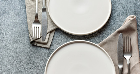 White craft plate, cutlery and napkin on dark stone table. Top view, copy space, Table setting. background for menu, layout, place for text , recipe background
