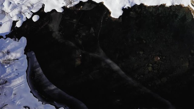 top view aerial over snowy blue alpine lake in sunny winter day .Europe Alps mountains outdoor establisher.4k drone overhead flight establishing shot