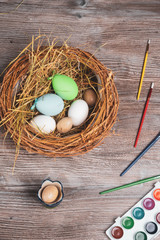 easter nest with eggs, paints and brushes