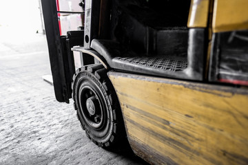 Close-up view of an old forklift truck seen at the entrance to a warehouse. Many scuff marks are seen on the side panelling. Seen parked near a loading bay.