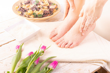 Young woman doing foot peeling, scrub using natural cosmetics. Home SPA.