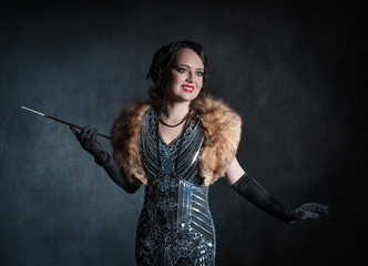 Beautiful elegant woman in retro 20 – 30 style with veil on dark background