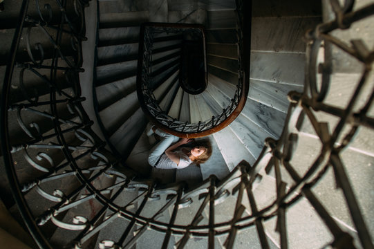 Beautiful girl with blond hair lies on spiral staircase