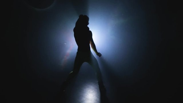 Hot muscular stripper like a macho shows performance alone. Man choreographer dances Striptease in silhouette in slowmo. Private erotic dance with torso. Male sexual body movements. Background light