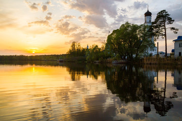 Panoramic view of the Raifa monastery from the lake. Sunset sky. Mirror reflection in the water. Beautiful russian nature. 