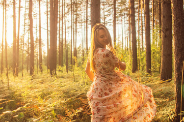 Portrait of young beautiful girl in summer dress in forest that dancing