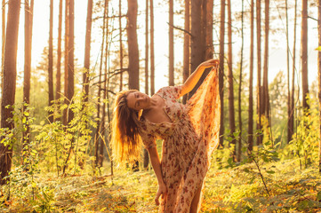 Portrait of young beautiful girl in summer dress in forest that dancing