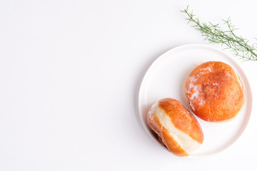 Homemade baked donut on a white ceramic plate on a light grey background. Flat lay.