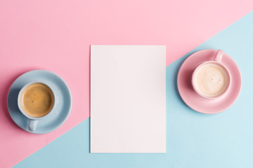 Creative pastel blue pink background with two ceramic cups of freshly brewed coffee drink and paper sheet.