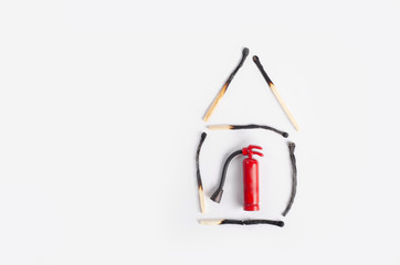 Fire insurance concept. Small house made of burnt matches with a miniature fire extinguisher inside