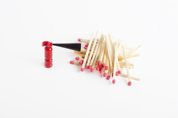 Tiny fire extinguisher close to a pile of unused matches, top-side view