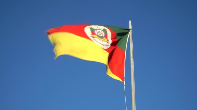 Beautiful flag of Rio Grande do Sul state waving in the wind on sunny summer day with blue sky. Concept of state, symbol, republic, Brazil, cultural identity, democracy, geography and politics.
